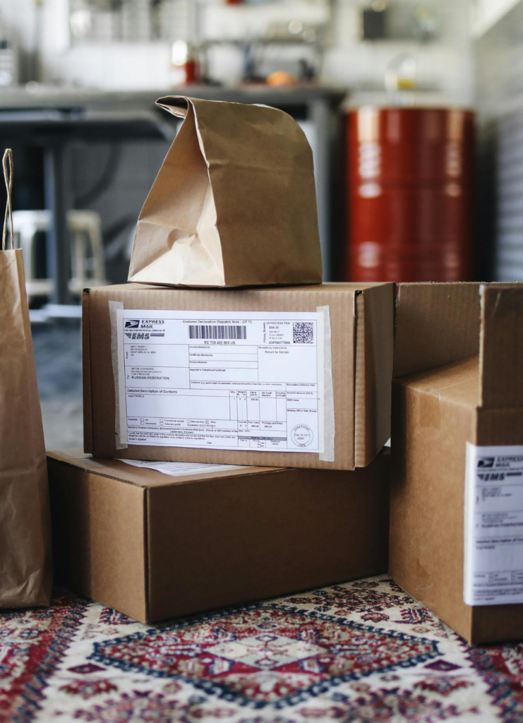 Mehrere braune Pakete und Versandkartons, die im Paketshop vom Mato Kiosk Wetzlar zur Abholung oder zum Versand bereitliegen